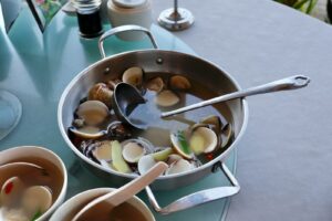 Steaming pot of clams with ginger and broth.